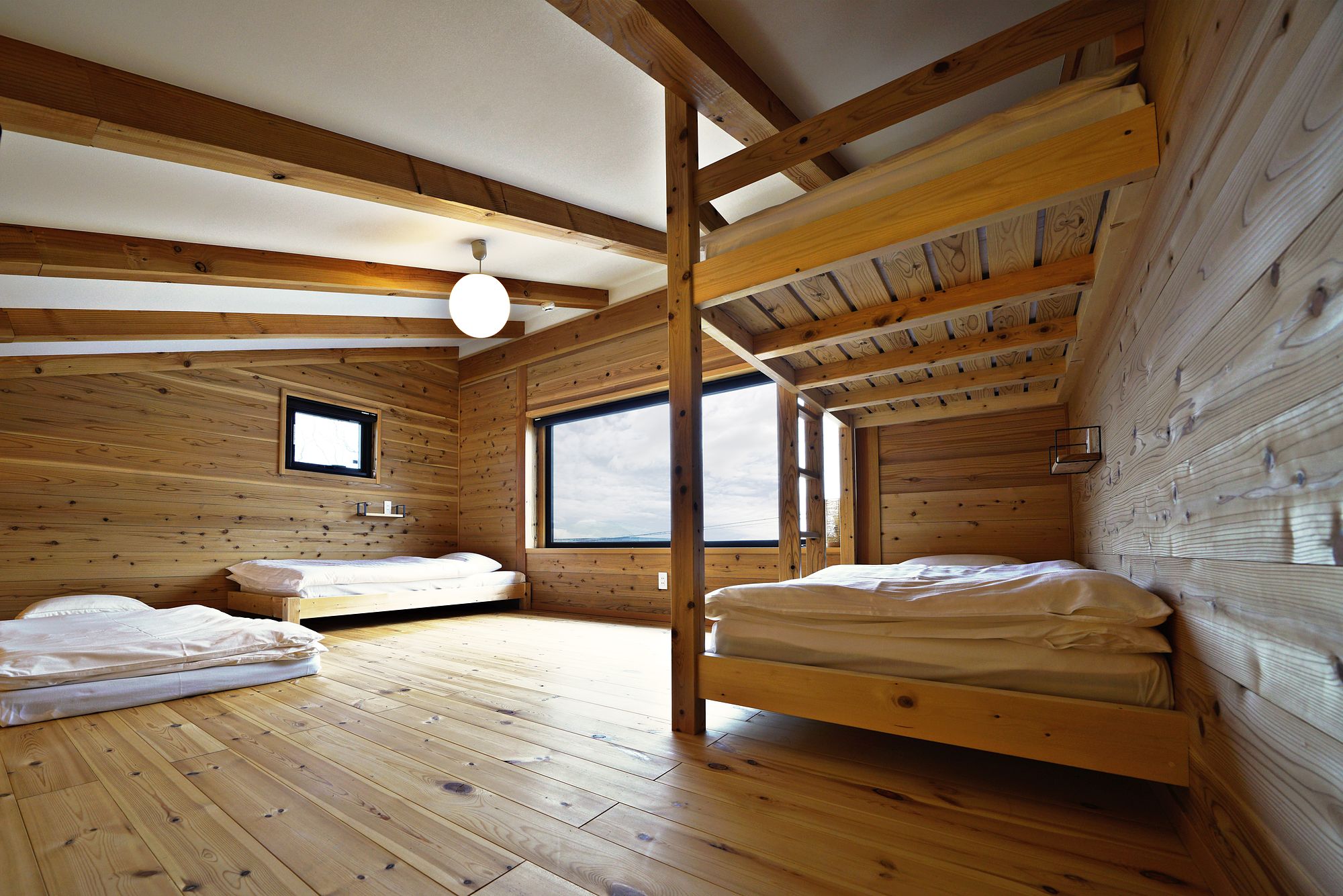 The loft by day: a single bed, a bed under a timber bunk frame and a futon on the floor