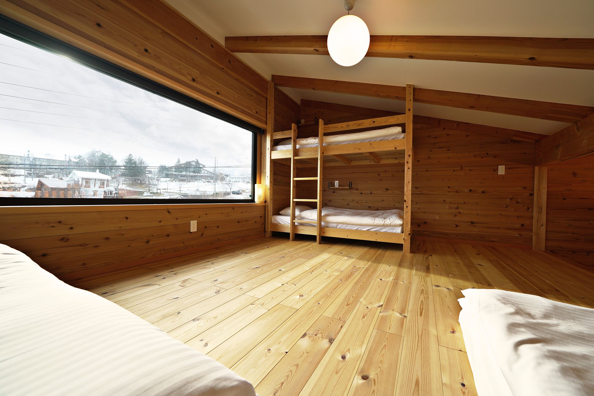 Timber bunk bed in the loft, with a wide window over Madarao village