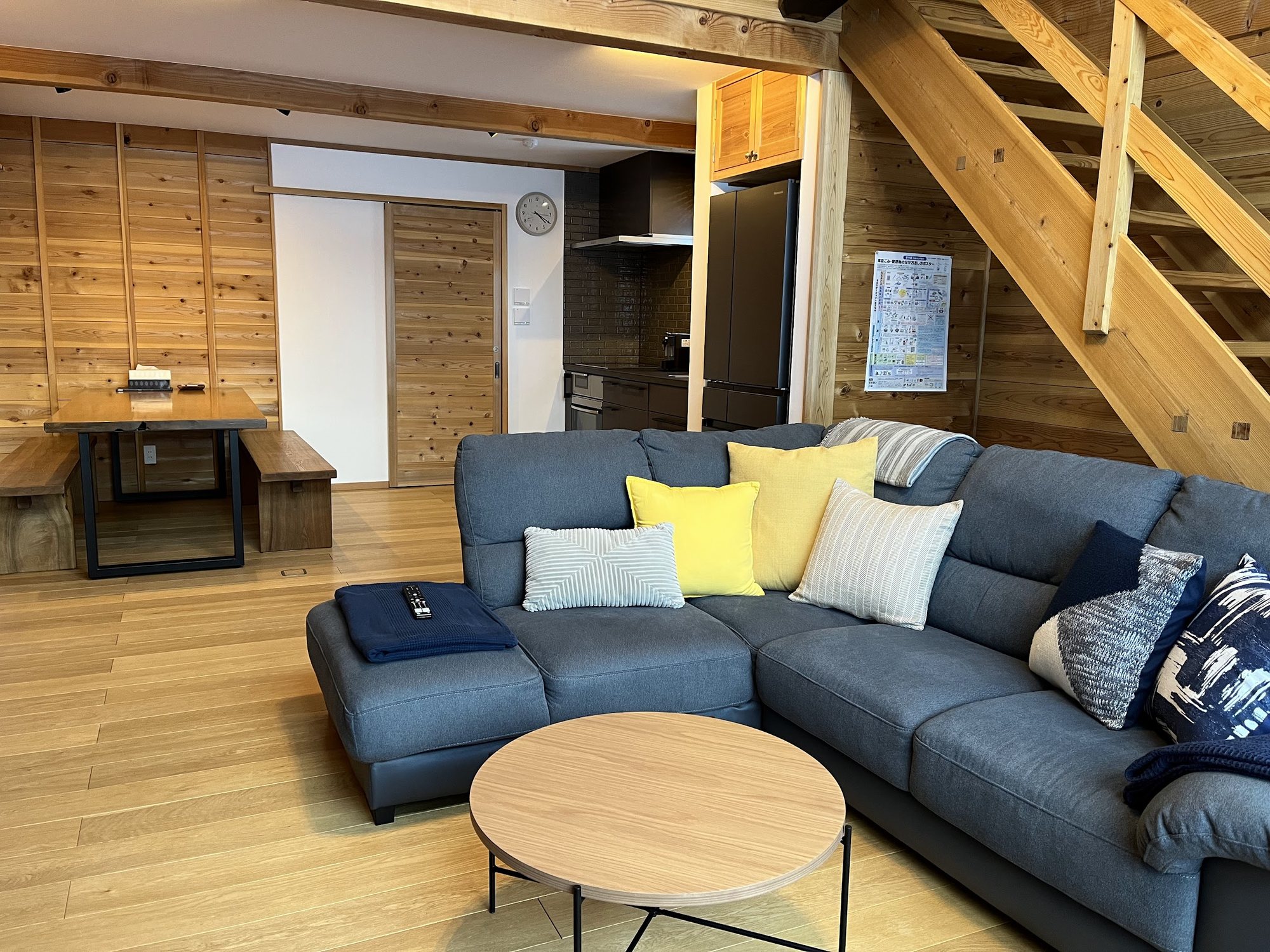 Sofa, timber dining table and benches, and the kitchen beyond