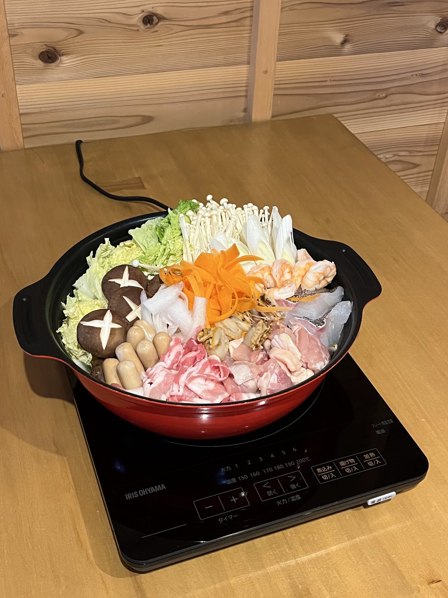 Nabe hotpot of vegetables, mushrooms, seafood and pork on a tabletop hob