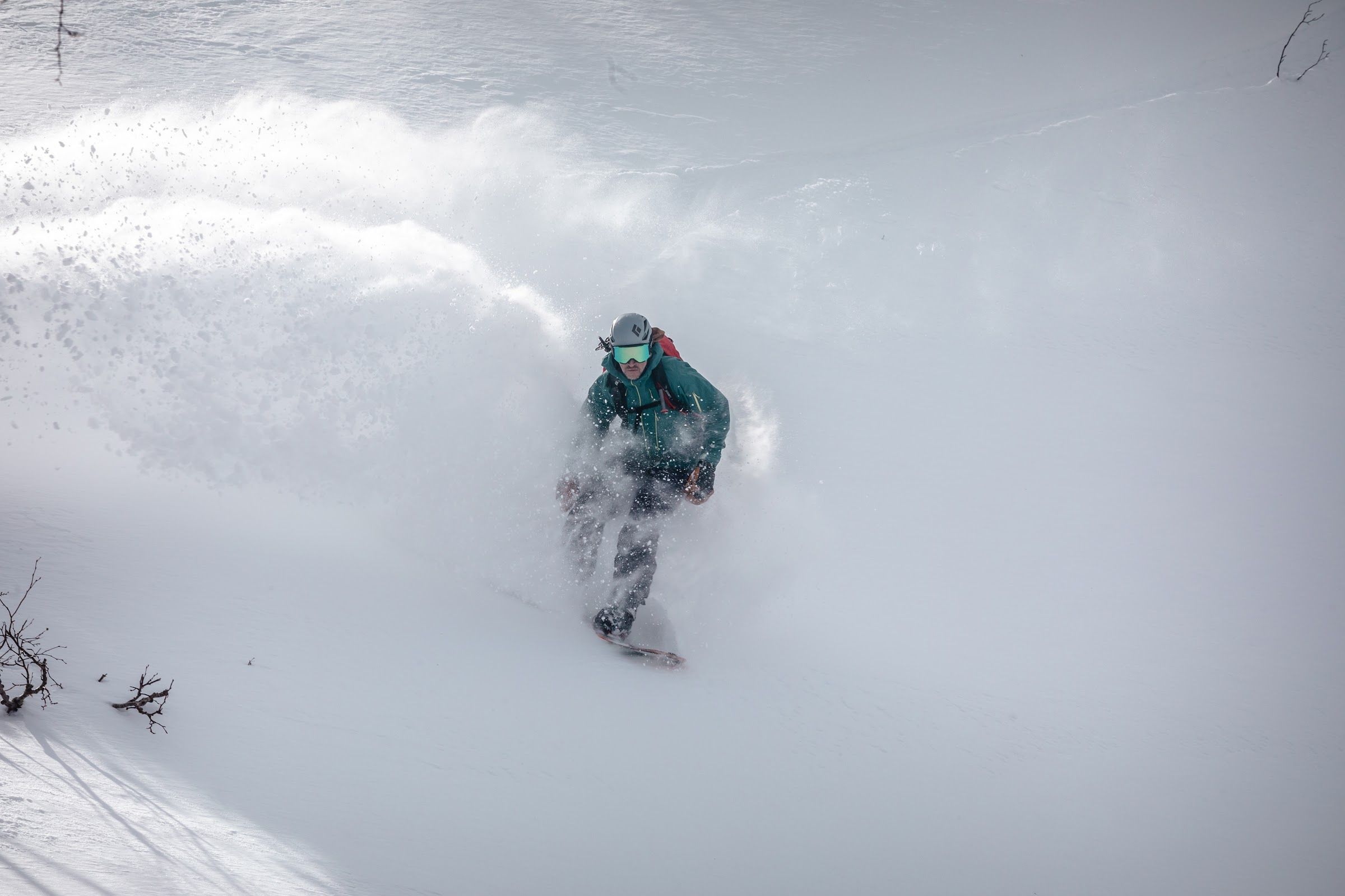 Snowboarder turning through deep powder in a spray of snow